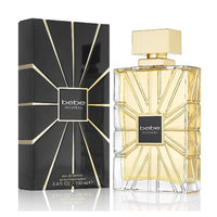 Bebe Nouveau perfume bottle with gold liquid next to black box with geometric line design